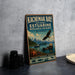 A vintage-style metal sign for the Kachemak Bay National Estuarine Research Reserve in Alaska, featuring an eagle, a sea otter, and a boat on the water.