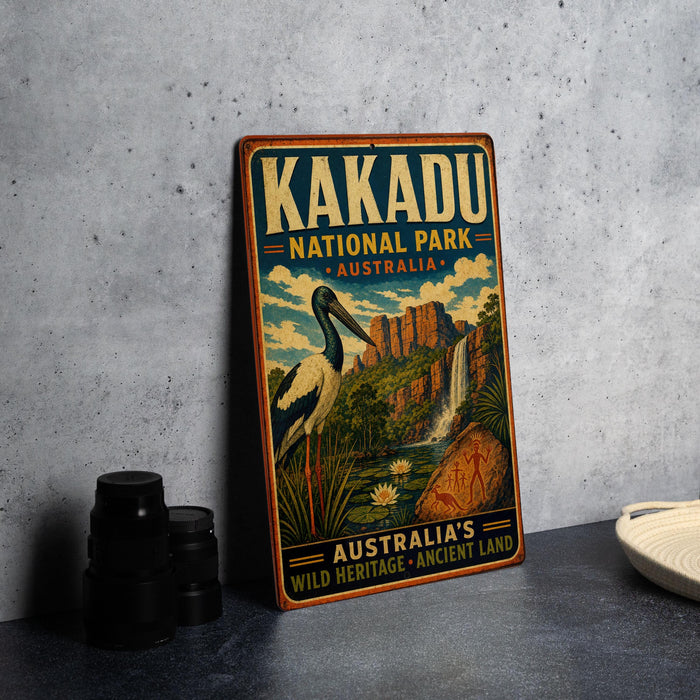 A vintage-style sign for Kakadu National Park, Australia, featuring an illustration of a bird and a waterfall, along with the text "Kakadu National Park - Australia - Australia's Wild Heritage - Ancient Land".