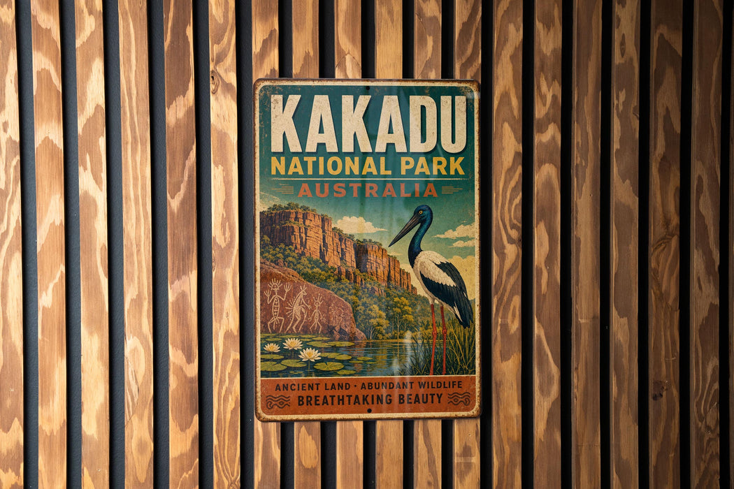 A vintage-style metal sign for Kakadu National Park in Australia, featuring an illustration of a bird and a landscape with a lake and mountains.