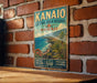 A vintage-style metal sign for the Kanio Natural Area Reserve in Hawaii, featuring a tropical landscape with palm trees and a blue ocean.