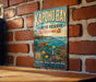 A vintage metal sign for the Kapoho Bay Marine Reserve in Hawaii, featuring a turtle and tropical flowers, is displayed on a brick wall.