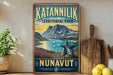 A vintage-style sign for Katanilik Territorial Park, featuring a scenic landscape with mountains, a lake, and a rock formation.