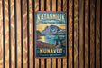 A vintage-style metal sign for Katanvilik Territorial Park, featuring a scenic landscape with mountains, a lake, and a rock formation.