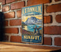 A vintage-style metal sign for Katanningik Territorial Park, featuring a scenic landscape with mountains, a lake, and a rock formation.