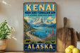 A vintage-style sign for the Kenai Mountains Turn Again Arm National Heritage Area in Alaska, featuring a scenic mountain landscape with a lake and a moose.