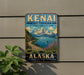 A vintage metal sign for Kenai Mountains Turn Again Arm National Heritage Area in Alaska, featuring a scenic mountain landscape with a lake and wildlife.