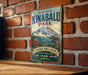 A vintage metal sign with the text "Welcome to Kinabalu Park" and a mountain landscape, mounted on a brick wall.