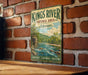 A vintage-style metal sign for the Kings River Natural Area in Arkansas, featuring a scenic illustration of a river surrounded by mountains and lush greenery.