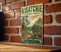 A vintage-style metal sign for the Kisatchie National Forest in Louisiana, featuring a scenic landscape with a lake and pine trees.