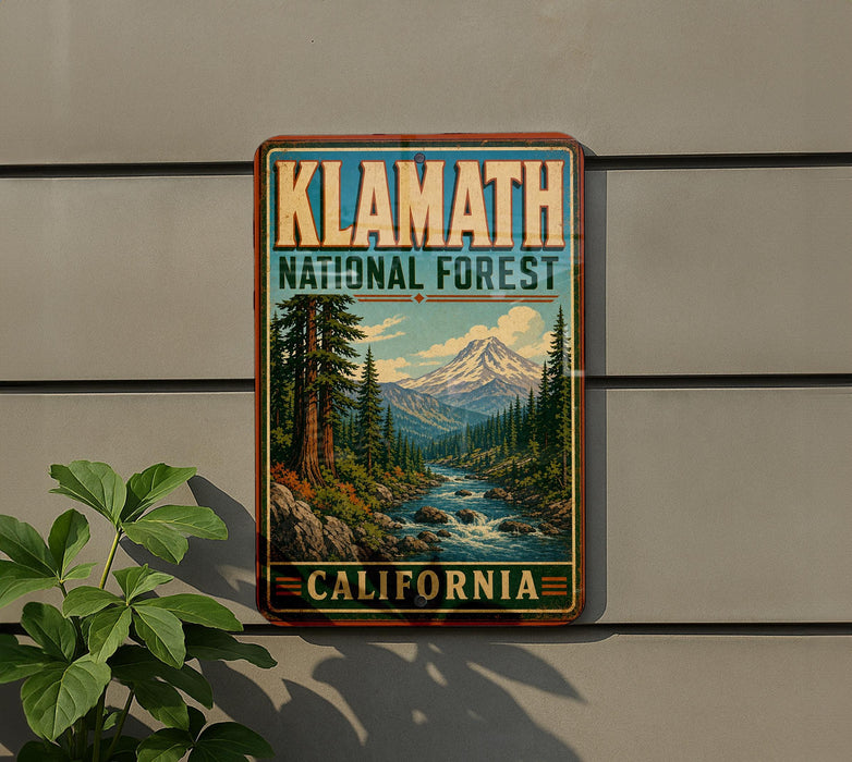 A vintage-style metal sign for Klamath National Forest in California, featuring a scenic landscape with a mountain, river, and pine trees.