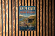 A vintage metal sign for Knife River Indian villages, located in North Dakota, is displayed on a wooden wall.
