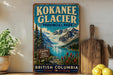 A vintage-style sign for the Kokanee Glacier in British Columbia, Canada, featuring a scenic mountain landscape with a lake and pine trees.
