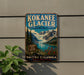 A vintage-style metal sign for the Kokanee Glacier in British Columbia, Canada, featuring a scenic mountain landscape with a lake and pine trees.