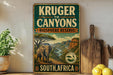 a vintage-style sign for Kruger to Canyon Biosphere Reserve in South Africa, with a painting of an elephant and a mountainous landscape.