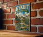 A vintage-style metal sign for the Rockefeller Estate in New York, featuring an illustration of the estate's gardens and fountain.