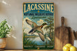 A vintage-style sign for the Lacasse National Wildlife Refuge in Louisiana, featuring an illustration of a duck in flight over a marshy area with trees and water.