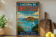 A vintage-style metal sign for Laguna di Orbetello, Italy, featuring a scenic image of the island and its surroundings.