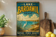 A vintage-style sign for Lake Bardawil in Egypt, featuring a seagull and a scenic landscape, is displayed on a shelf next to a wooden cutting board and a potted plant.