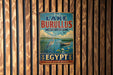 a vintage metal sign with a nature-themed illustration, mounted on a wooden wall.