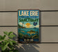 A vintage-style metal sign for Lake Erie National Marine Sanctuary in Ohio, featuring a lighthouse, fish, and a sunset over the water.