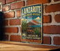 A vintage-style metal sign for Lanzarote Biosphere Reserve in Spain, featuring a desert landscape with cacti and mountains.