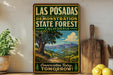 A vintage-style sign for the Las Posadas State Forest in California, featuring a scenic landscape with a tree, mountains, and a winding path.