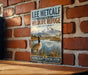 A vintage-style sign for the Lee Metcalf National Wildlife Refuge in Montana, featuring a goose and a mountain landscape.