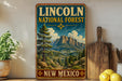 A vintage-style sign for the Lincoln National Forest in New Mexico, featuring a mountain landscape with pine trees and a cloudy sky.
