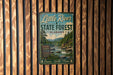 A vintage metal sign for Little River State Forest in Alabama, featuring a scenic image of a river surrounded by trees and mountains.