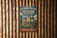 A vintage metal sign for the Lockwood-Mathews Mansion Museum in Connecticut, featuring an illustration of a historic mansion and the text "A NATIONAL HISTORIC LANDSCAPE" and "CONNECTICUT".