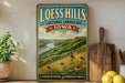 A vintage-style sign for Loess Hills, Iowa, featuring a scenic landscape with a river and mountains.