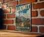 A vintage-style metal sign for the Loowit Trail in Washington, featuring a mountain landscape and a trail sign.