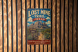 A vintage-style sign for Lost Mine Trail in Texas, featuring a mountain landscape and trail signs, mounted on a wooden wall.