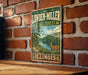 A vintage metal sign for Lowden-Miller State Forest in Illinois, featuring a scenic illustration of a deer in the foreground and a river in the background.