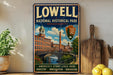 A vintage-style metal sign for Lowell National Historical Park in Massachusetts, featuring an illustration of a historic building and a river.