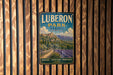 A vintage metal sign with the text "LUBERON PARK FRANCE" and "NATURE - HERITAGE - PROVENCE" is displayed on a wooden wall.