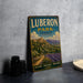 A vintage-style metal sign for Lubberon Park, France, featuring a scenic landscape with mountains, olive groves, and a winding path.