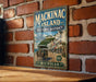 A vintage-style metal sign for Mackinac Island, featuring an illustration of a horse-drawn carriage and the text "Mackinac Island Historic District" and "Michigan".