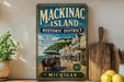 A vintage-style metal sign for Mackinac Island, Michigan, featuring an illustration of a horse-drawn carriage and a scenic coastal town.