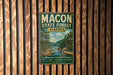 A vintage metal sign for the Macon State Forest in Alabama, featuring a scenic illustration of a forest landscape with a river.