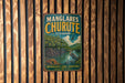 A vintage metal sign with the text "MANGLARES CHURUTE ECUADOR NATURA VIDA AVENTURA" hanging on a wooden wall.