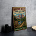 A vintage-style metal sign advertising Maroon Bells Four Pass Loop in Colorado, featuring a scenic mountain landscape with a lake and trail.