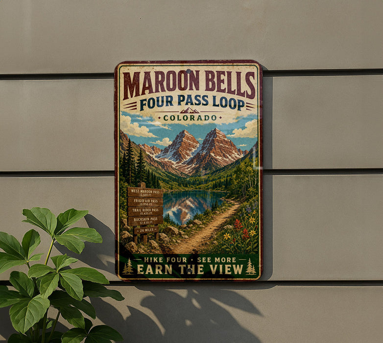 A vintage-style metal sign for Maroon Bells Four Pass Loop in Colorado, featuring a scenic mountain landscape with a lake and trail.