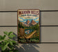 A vintage-style metal sign for Maroon Bells Four Pass Loop in Colorado, featuring a scenic mountain landscape with a lake and trail.