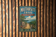 A vintage metal sign for the Mattabesett Trail in Connecticut, featuring a scenic illustration of a path leading through a forested landscape with a lake in the background.