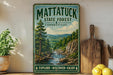 A vintage metal sign for Mattatuck State Forest in Connecticut, featuring a scenic landscape with a river and mountains.