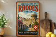 A vintage-style poster of the Medieval City of Rhodes, Greece, featuring a castle and a Greek flag, is displayed on a wall next to a wooden cutting board and a potted plant.