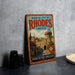 A vintage metal sign for the Medieval City of Rhodes, Greece, featuring a castle and a cross, is displayed on a gray countertop next to some black camera lenses.