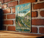 A vintage metal sign for "Mélérdall Park" in Luxembourg, featuring a scenic mountain landscape with a river.