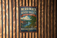 A vintage-style metal sign for Merrimack River Valley, Massachusetts, featuring a scenic landscape with a river and buildings.